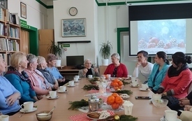 Grupa ludzi patrzy w kierunku kobiety, kt&oacute;ra opowiada historię