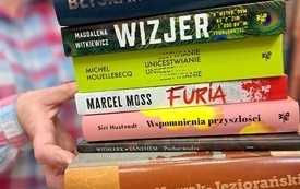 Bibliotekarka trzyma w rękach stos książek