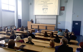 Aula studencka wypełniona uczestnikami spotkania. Na m&oacute;wnicy kobieta z długimi włosami. 