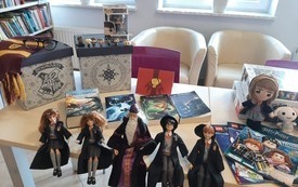 Na stole leżą lalki, bohaterowie z książki o Harrym Potterze oraz inne gadżety związane z czarodziejem. 