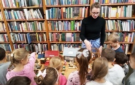 Dzieci oglądają wystawę wraz z bibliotekarką.