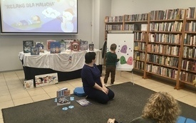 Sala biblioteczna, bibliotekarka prowadzi zajęcia dla dzieci.