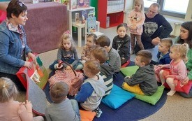 Bibliotekarka pokazuje grupie dzieci książkę z filcu o Czerwonym Kapturku. 