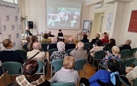 Uczestnicy spotkania oglądają film wyświetlany na ekranie projekcyjnym.