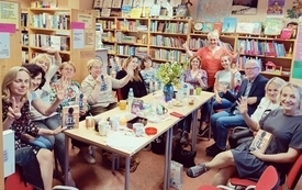 Grupa czytelnik&oacute;w pozuje do zdjecia w bibliotece trzymając w rękach książki