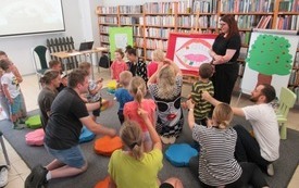 Rodzice wraz z dziećmi siedzą na podłodze w bibliotece