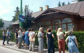 Bibliotekarze pod zabytkowym budynkiem, słuchają przewodniczki.