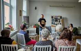 Michał  Smielak, stoi przed grupą ludzi i opowiada. 