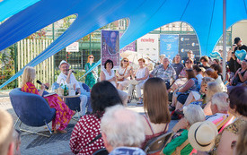 Pod niebieskim namiotem publiczność oraz gość spotkania.