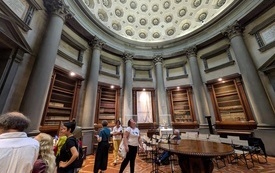 Grupa os&oacute;b stoi w okrągłej sali zabytkowej biblioteki