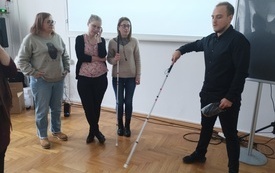 Mężczyzna z laską osoby niewidomej oraz trzy bibliotekarki.