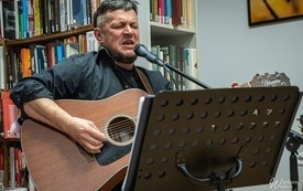 Muzyk śpiewający i grający na gitarze podczas występu. 